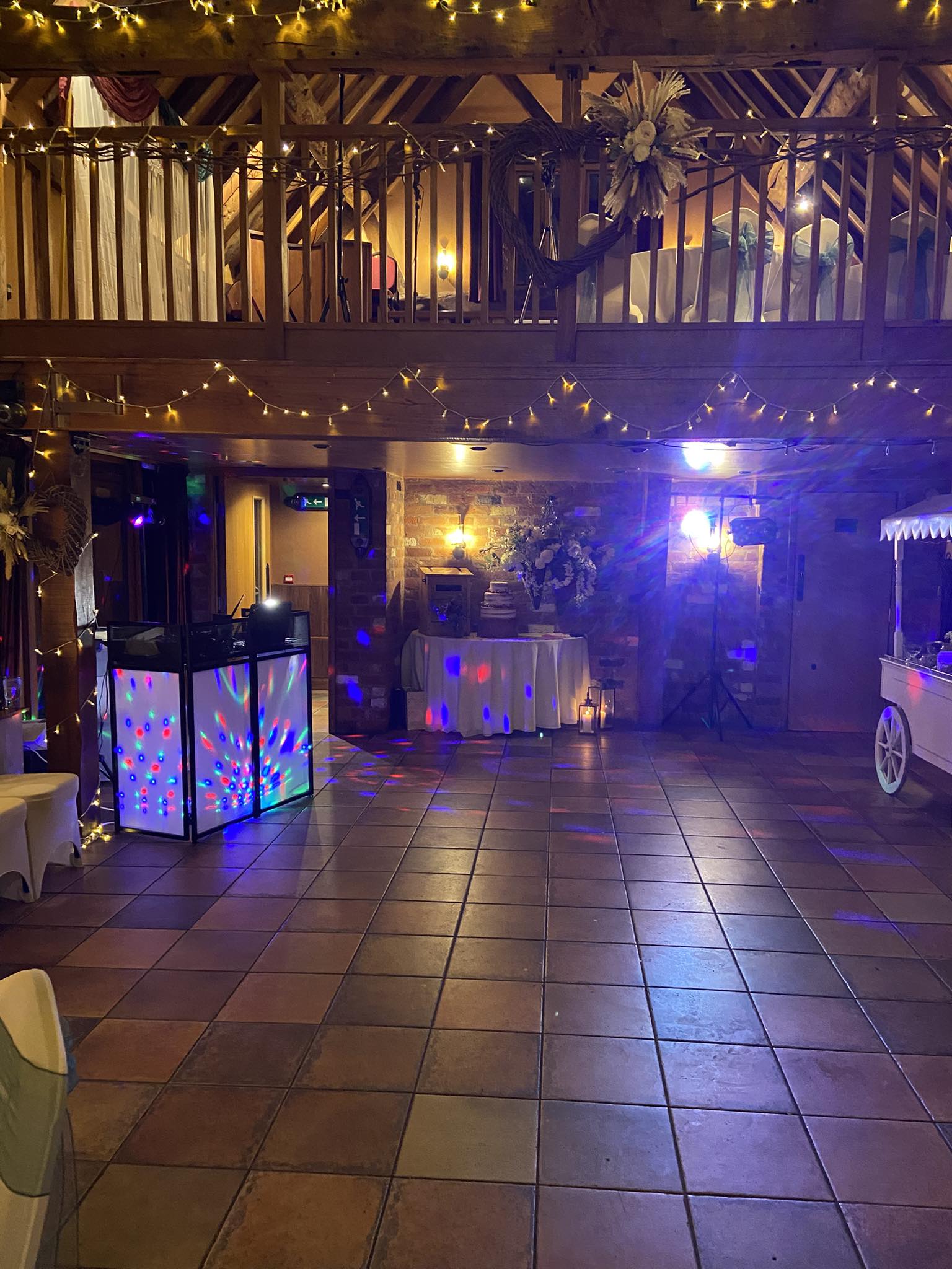 Rustic barn wedding venue setup with fairy lights and DJ booth