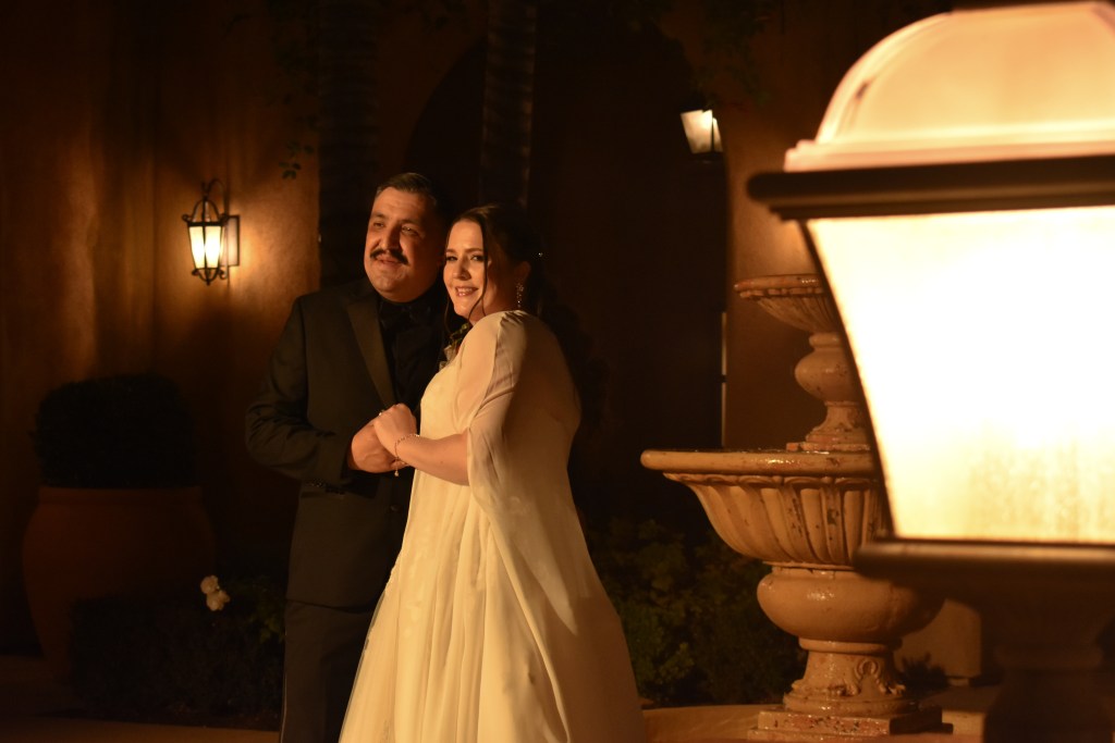 Bride and groom standing together at night with warm lantern lighting