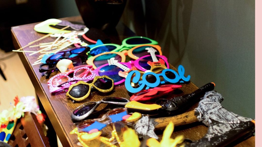 Colorful novelty sunglasses and party props on wooden surface