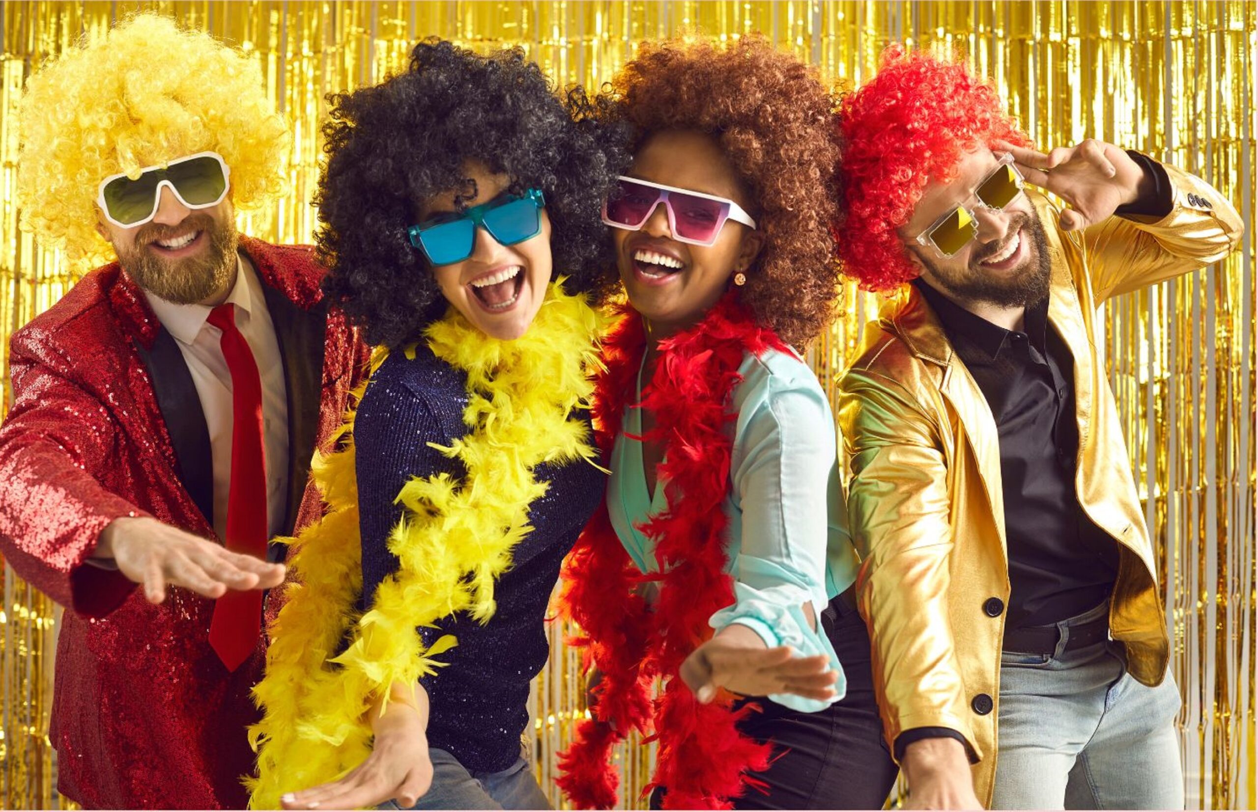 Four people in colorful wigs and sunglasses dancing at party