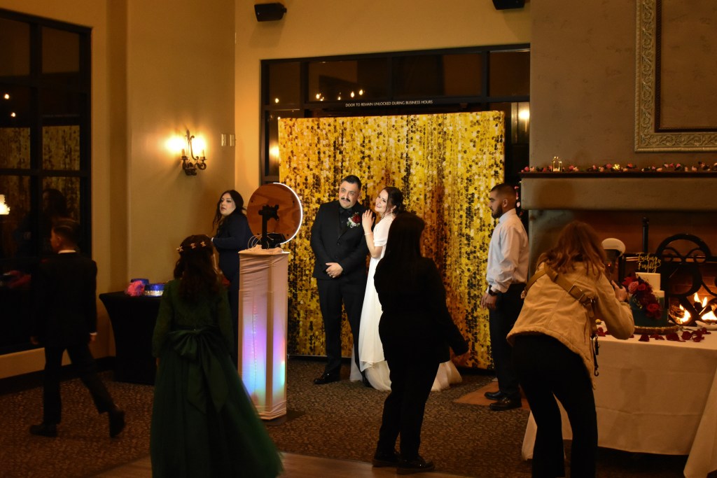 Guests gathered around photo booth with yellow sequin backdrop