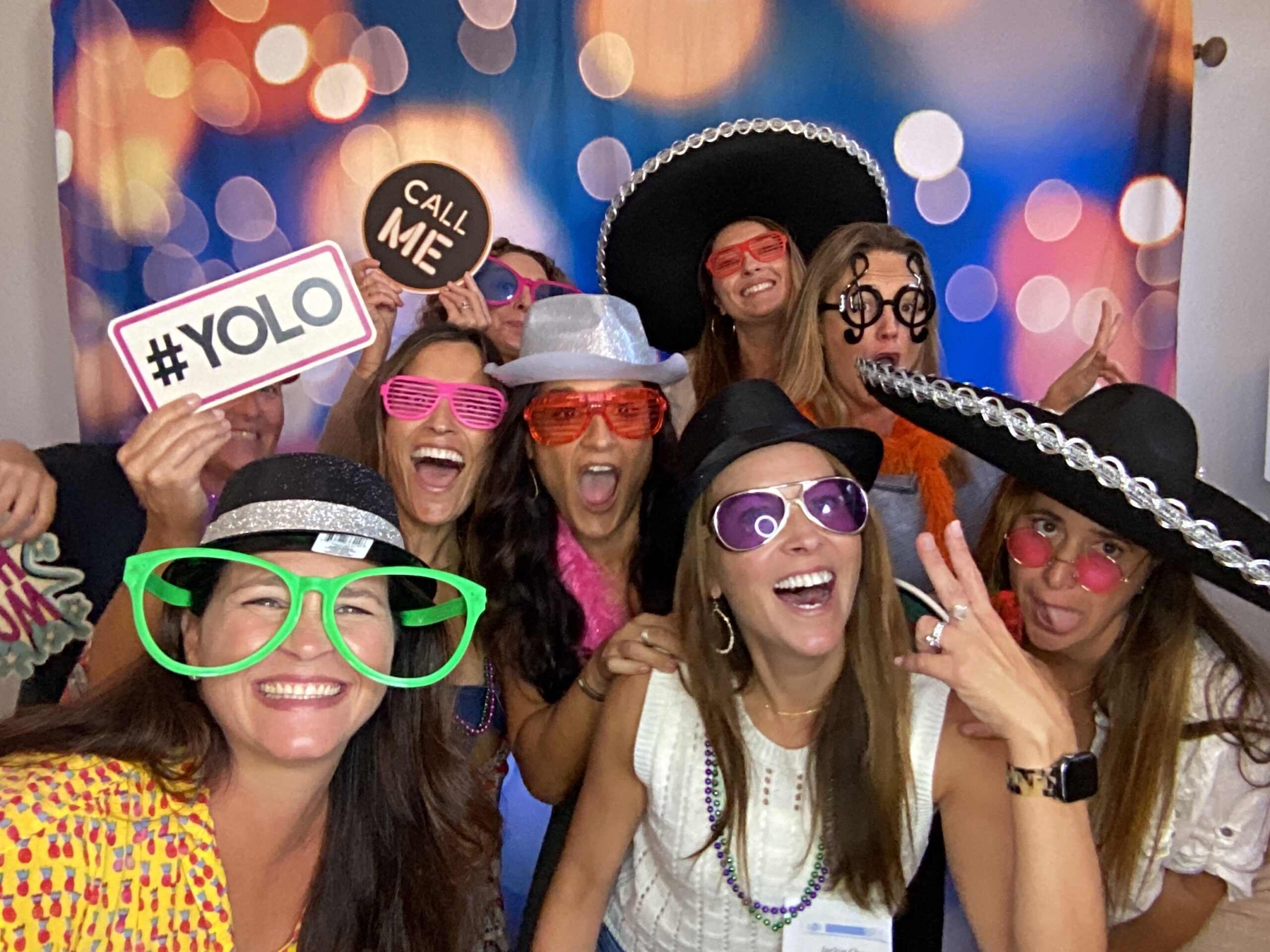 Women wearing novelty hats and glasses with bokeh background