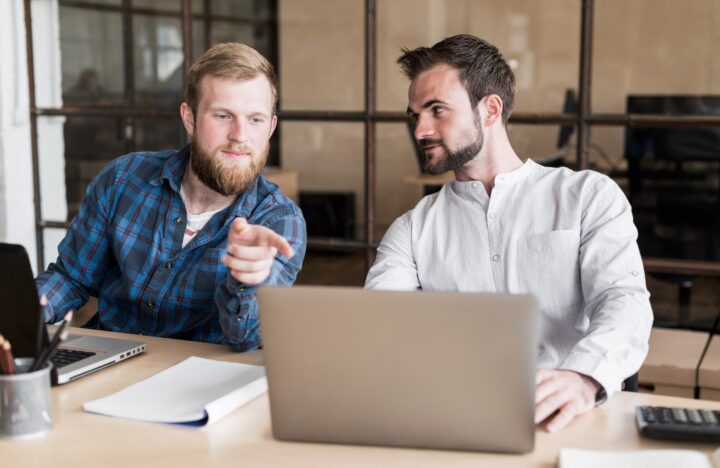 Zwei Berater diskutieren am Laptop über KI-Lösungen